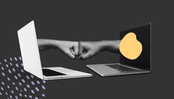 Dois computadores frente à frente. Deles, saem duas mãos com punhos fechados que tocam uma na outra.