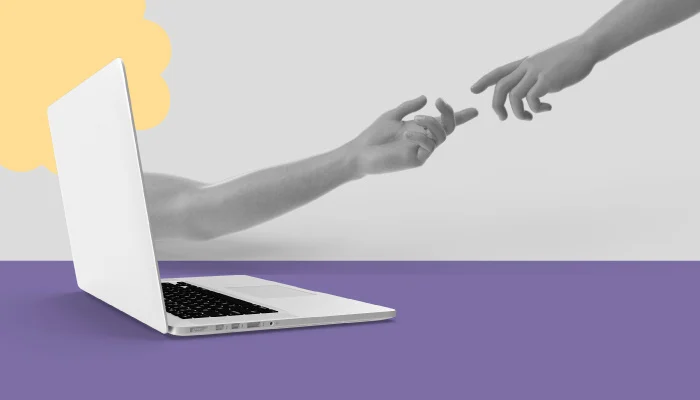 Um braço sai de um notebook. A mão toca em outra mão que vem em sua direção.