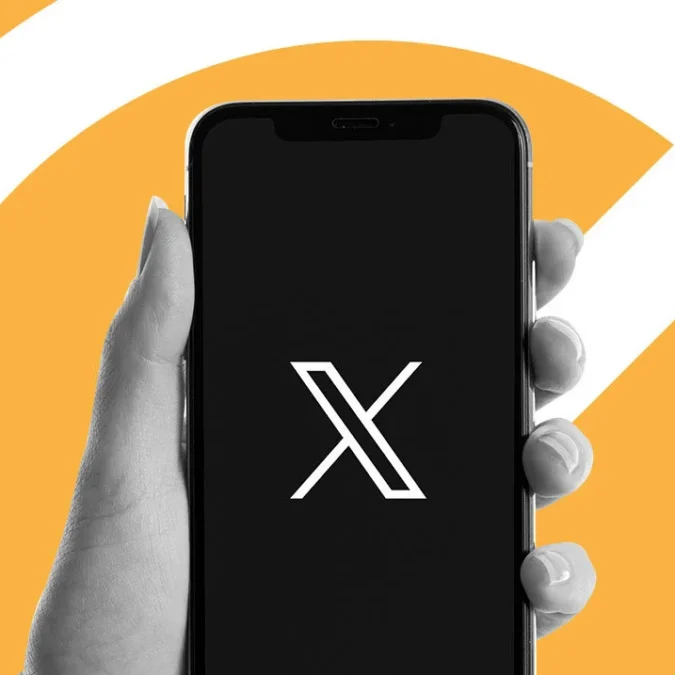 Fotomontagem de uma mã osegurand o celular com o logotipo da rede social X, o antigo Twitter